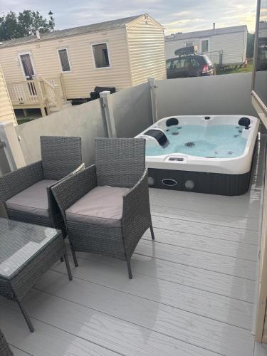a hot tub sitting on a patio with two chairs at Luxury Hot tub breaks at Sunnymede, Ingoldmells in Ingoldmells