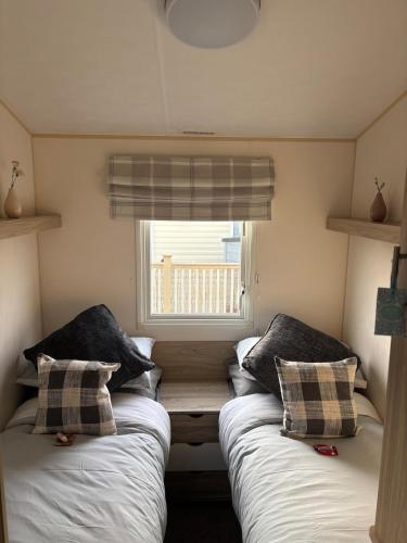 two beds in a small room with a window at Luxury Hot tub breaks at Sunnymede, Ingoldmells in Ingoldmells