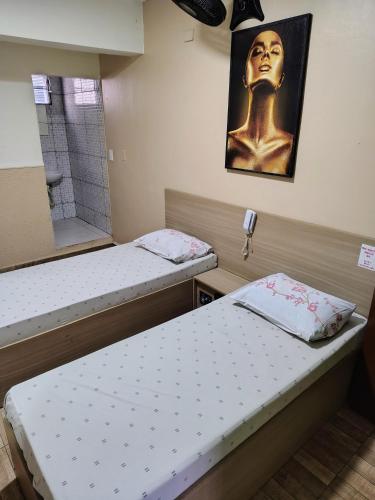 two beds in a room with a statue on the wall at Hotel indico in São Bernardo do Campo