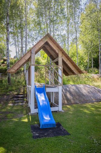 a playground with a blue slide in the grass at Large and newly built family home in Goteborg in Härryda