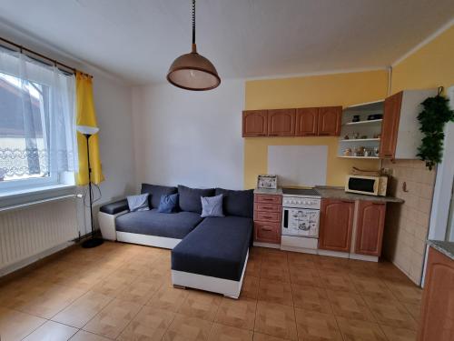 a living room with a blue couch and a kitchen at Ubytování na soutoku Lužnice a Nežárky in Veselí nad Lužnicí