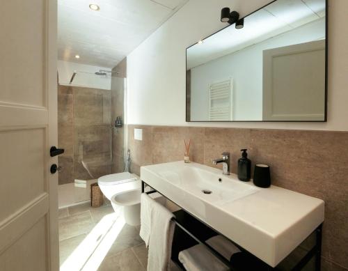 a bathroom with a sink and a toilet and a mirror at Masseria Kalandini in Corigliano dʼOtranto