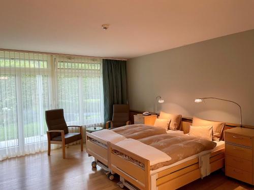 Schlafzimmer mit einem großen Bett, einem Schreibtisch und Stühlen in der Unterkunft Tertianum Parkresidenz Meilen in Meilen