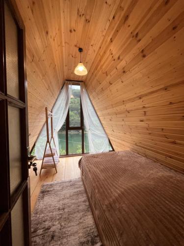 a bedroom with a bed in a wooden room at Lunea Cottage in Itʼkhvisi