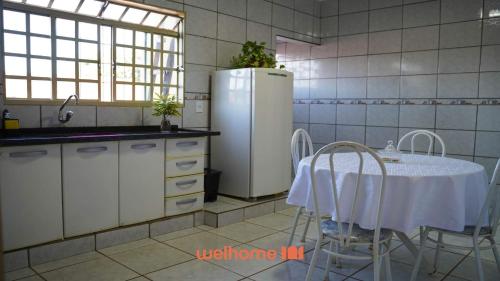 a kitchen with a table and a refrigerator at Apartamento em Delfinopolis com Vista Linda in Delfinópolis