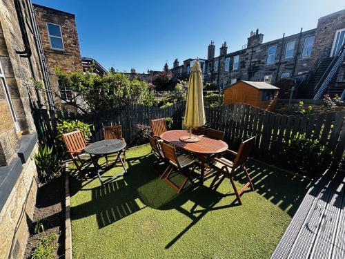 a patio with a table and chairs and a umbrella at Roomy home 1 level Free Parking in Edinburgh