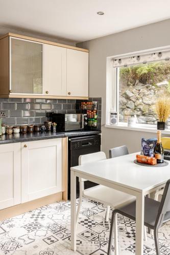 a kitchen with a white table and chairs at Zipworld Waterfalls Eryri Dogs Welcome 3 Bed sleeps 5 in Blaenau-Ffestiniog