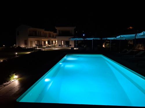 a blue swimming pool at night with a house in the background at SeaSide Village in Politiká