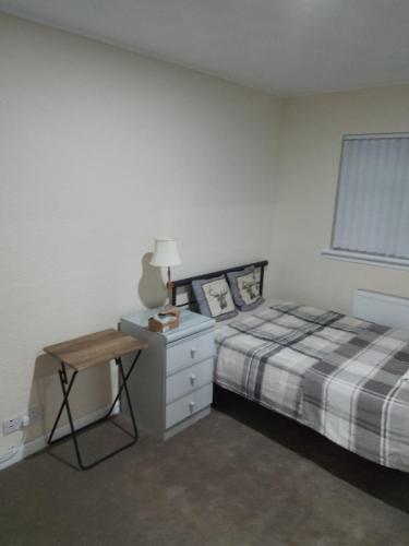 a bedroom with a bed and a table and a window at Studio Twenty One in Whitburn