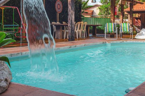 a water fountain in a swimming pool with chairs at Pousada Bosque das Borboletas in Sabará