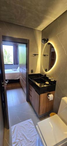 a bathroom with a sink and a mirror and a bed at City Zen Studios in Sao Jose do Rio Preto