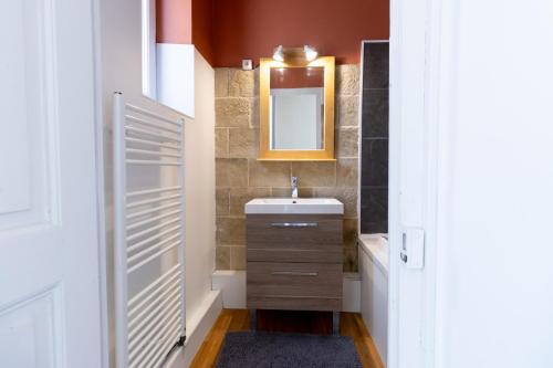 une salle de bain avec un lavabo et un miroir dans l'établissement Maison de ville au cœur de Saint Pierre en Auge, à Saint-Pierre-sur-Dives