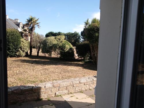 une porte ouverte menant à une cour plantée de palmiers dans l'établissement Le Crouesty résidence Bretagne Douce, piscine été, linge en option, à Arzon