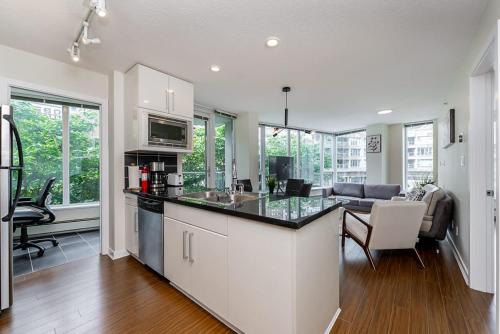 a kitchen with a counter top and a living room at Spacious Downtown Condo with Pool Gym & Parking in Vancouver