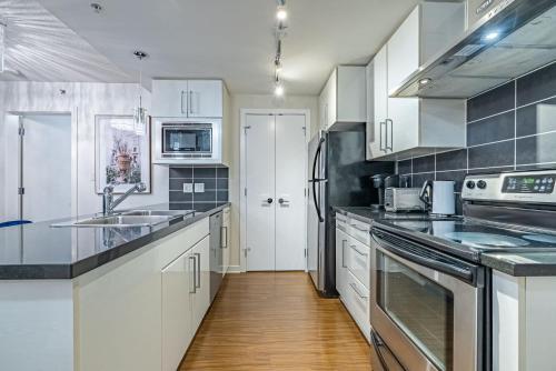 a kitchen with white cabinets and stainless steel appliances at Downtown Condo with Great City Views in Vancouver