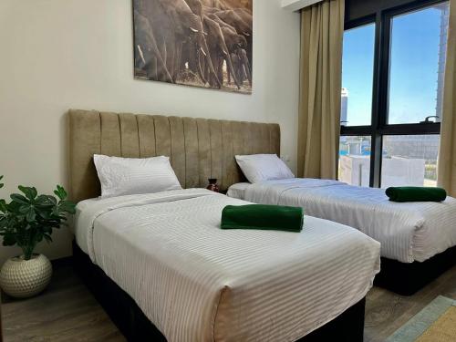 two beds in a room with a window at Zed Sheikh Zayed modern Apartment in Sheikh Zayed