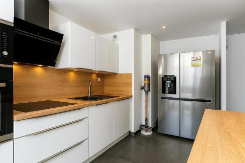 une cuisine avec des armoires blanches et un réfrigérateur en acier inoxydable dans l'établissement Large and beautiful apartment with panoramic sea views, à Marseille