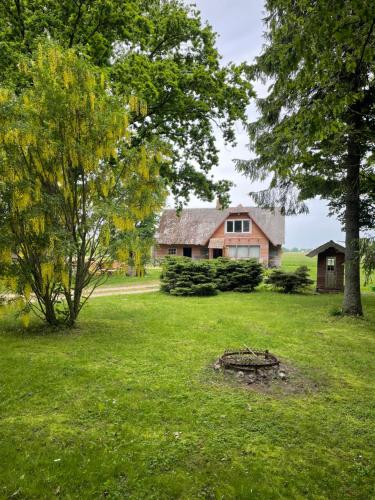 a house in the middle of a yard with trees at Holiday house Mežmuiža in Rucava