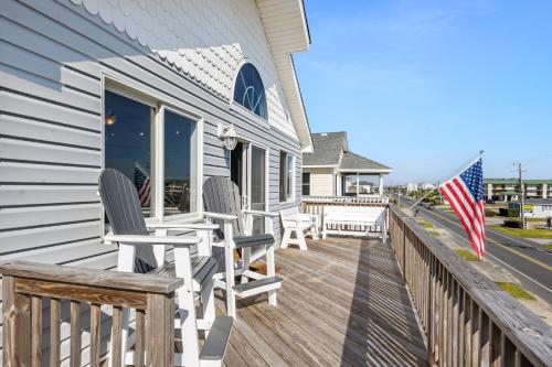 a deck with two chairs and an american flag at Coasties Ocean Breeze in Kill Devil Hills