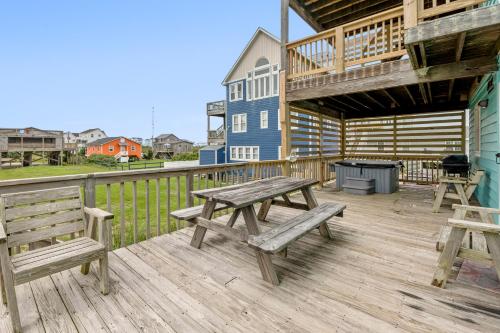 a picnic table and benches on a deck with a house at Color Me Beachy in Rodanthe