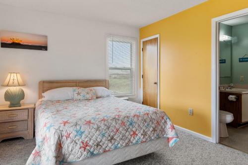 a small bedroom with a bed and a bathroom at Color Me Beachy in Rodanthe