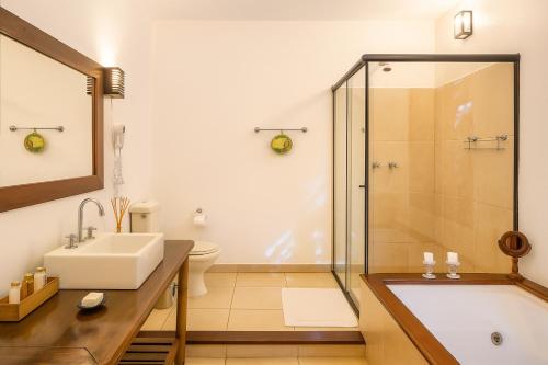 a bathroom with a tub and a sink and a shower at Pousada Maya in Alto Paraíso de Goiás