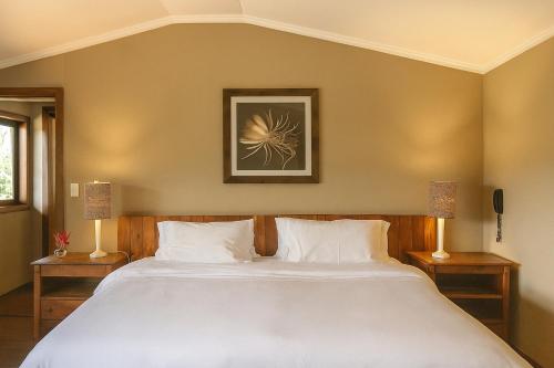 a bedroom with a large white bed with two lamps at Pousada Maya in Alto Paraíso de Goiás