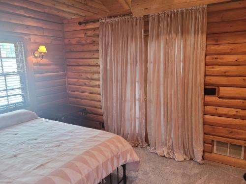 una camera da letto con un letto e una finestra con tende di Hidden Cove - Beauty On The Lake! a Oscoda