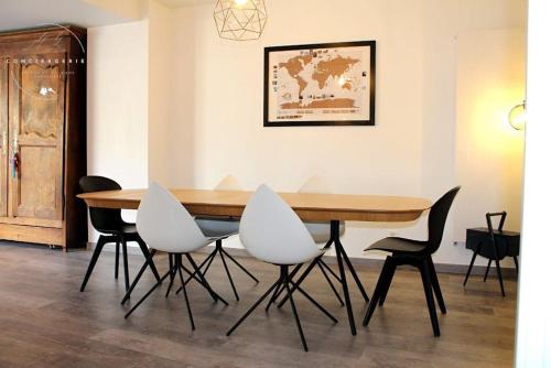 une table de salle à manger avec des chaises blanches autour dans l'établissement Maison Familiale - Proche Fontainebleau Paris, à Champagne-sur-Seine