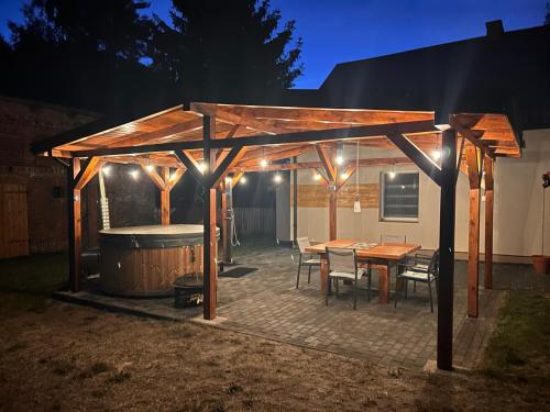 a wooden pergola with a table and a tub at Dom Nad Jeziorem Trzy Tonie in Silna Nowa
