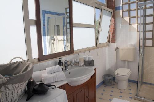 a bathroom with a sink and a toilet and a mirror at Rifugio sul Mare in San Leone