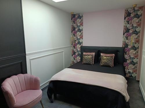 a bedroom with a bed and a pink chair at Cocon romantique avec jacuzzi extérieur in Rosières-près-Troyes