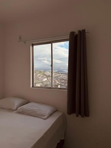 a bedroom with a window with a view of a city at Nox Temporada Flat 201 com AR, a 5 Min da Feira de Caruaru in Caruaru