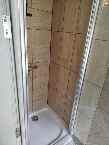 a bathroom with a shower with a white tub at Smallest bird's HAVEN in Bloxwich