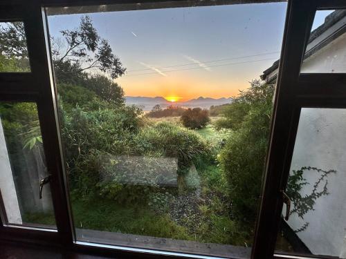 a view of a sunset from a window at Tievemore - Connemara Bayfront Retreat in Moyard
