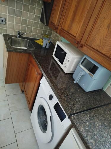 a kitchen with a washing machine and a microwave at Smallest bird's HAVEN in Bloxwich
