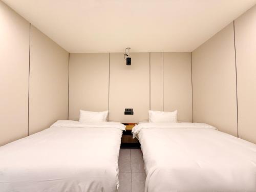 two beds in a room with white walls at Shanghai Zhuzhu Hotel - 24-hour free airport pick-up and drop-off at Pudong Airport in Shanghai