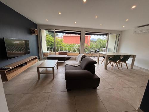 a living room with a couch and a tv and a table at Appartement 3 pièces à 5 min de la plage in La Seyne-sur-Mer