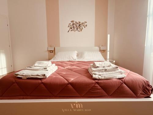 a large red bed with towels on top of it at Villa Marelago Guest House in Lido Di Fondi