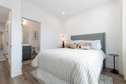 a white bedroom with a large bed with white sheets at Brand NEW Townhome! Luxury AND Convenience - NO EXTRA FEES! in Grand Junction