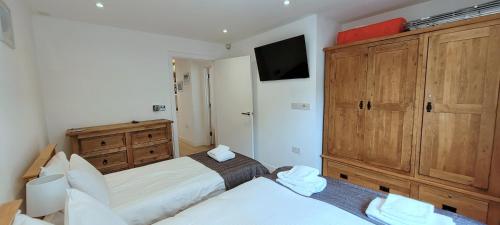 a bedroom with two beds and a dresser at 4 Fistral Beach Apartments, Newquay, TR7 1FR in Crantock