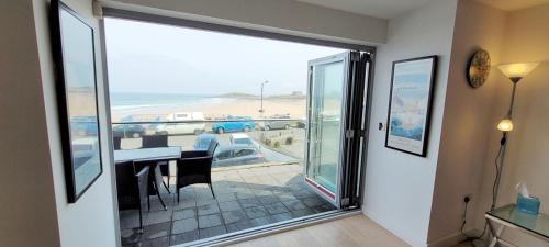 a dining room with a sliding glass door with a view of the ocean at 4 Fistral Beach Apartments, Newquay, TR7 1FR in Crantock