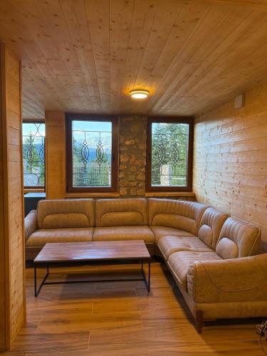 a living room with a leather couch and two windows at Villa Peak in Peje