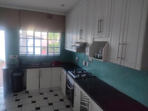 a kitchen with white cabinets and a black counter top at Guest house on barnes in Johannesburg