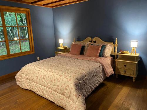 a bedroom with a large bed and two night stands with lamps at Yellow House Santa Clara in Bocaina de Minas
