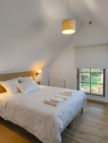 une chambre avec un grand lit blanc avec des serviettes dessus dans l'établissement LES PATICHERES - L'Etable avec accès piscine, à Biville-la-Baignarde