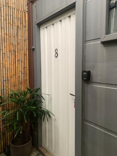 a garage door with the number eight next to a plant at Estúdios Conteiners de 02 a 04 hóspedes região lapa in Sao Paulo