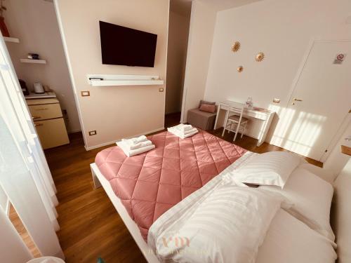 a bedroom with a pink bed and a television at Villa Marelago Guest House in Lido Di Fondi