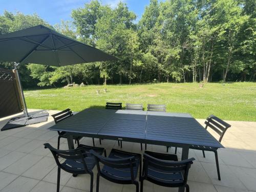 a picnic table with chairs and an umbrella at Gîtes du Château de Malcombe in Rillé
