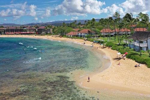 an aerial view of a beach with people in the water at Hale Kai‘opua at Kukui'ula in Koloa